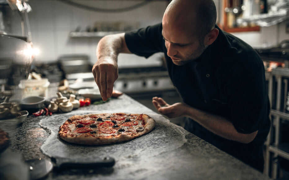 Putting seasoning on pizza